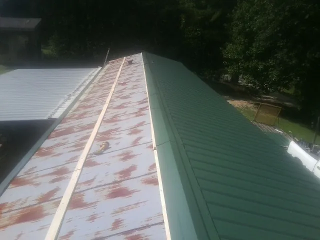 Old rusted panels beside newly installed green metal roofing — Wind Damage Roof Repair by Roofing Brothers in Monticello